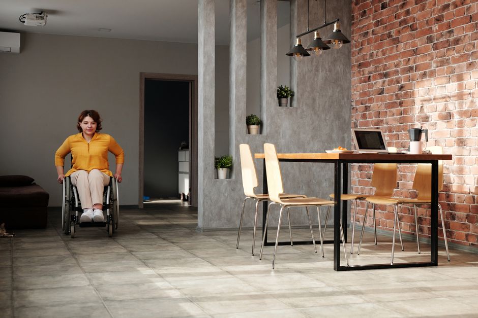 A woman in a wheelchair navigating a modern home office space with brick walls.